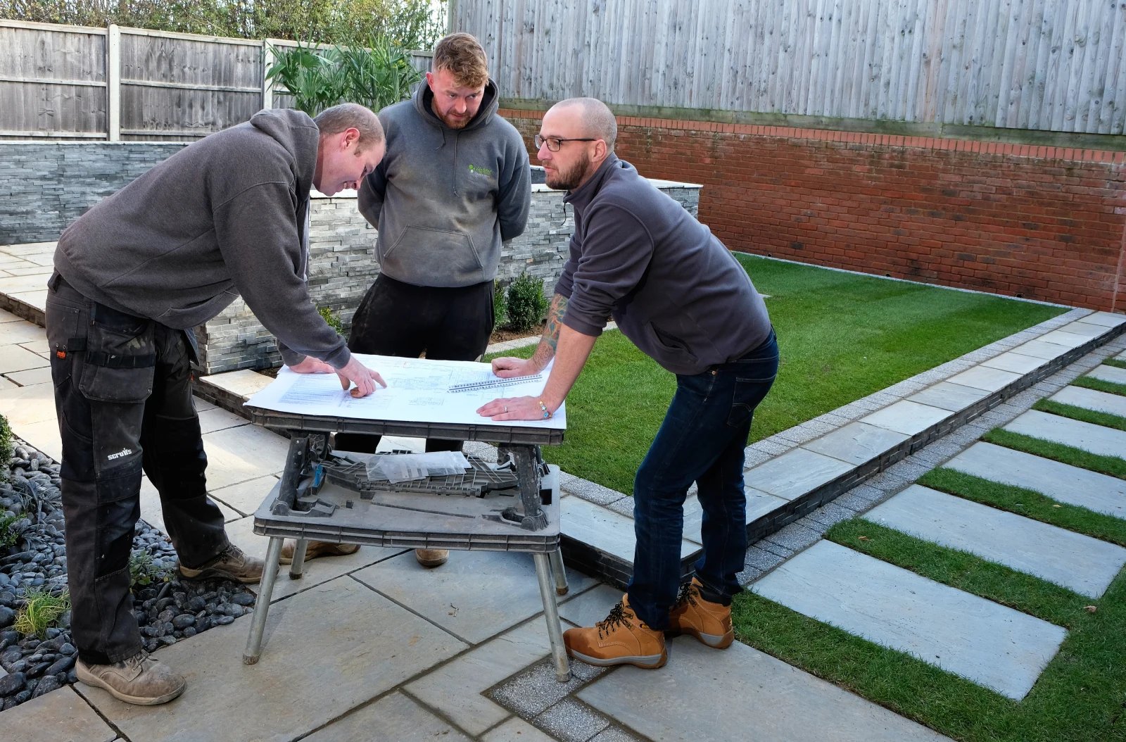 Three members of the Habitat Landscapes team reviewing plans together on site.